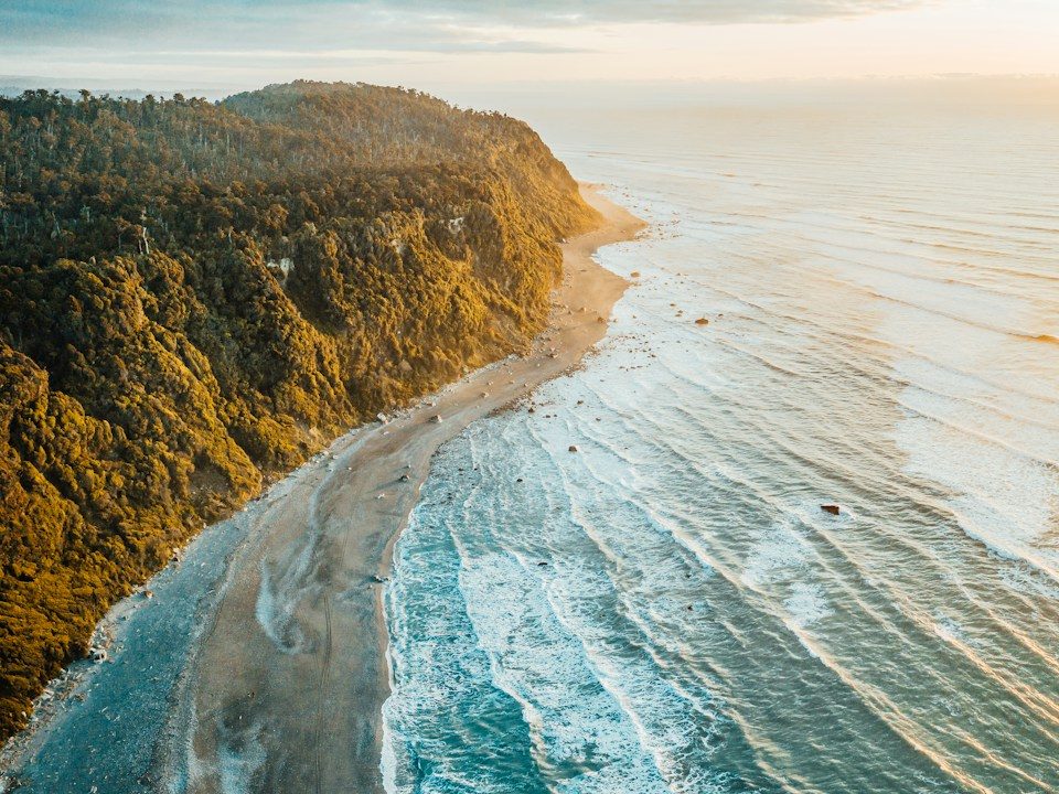 an aerial view of a beach and a forested area